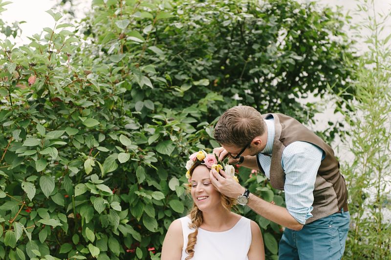 marié remet une fleur dans la couronne de fleurs de la mariée