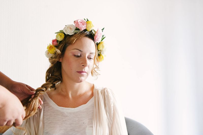 mariée se faisant coiffer tresse et couronne de fleurs